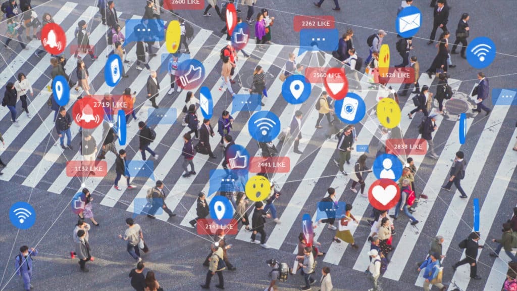 A group of people crossing an intersection with various social media icons popping out from them.