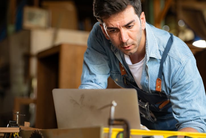 A small business owner working on a laptop in their workshop