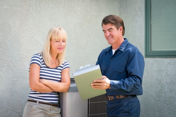 An HVAC technician talking to a customer