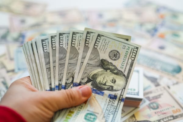 Hands holding a large pile of 100 dollar bills