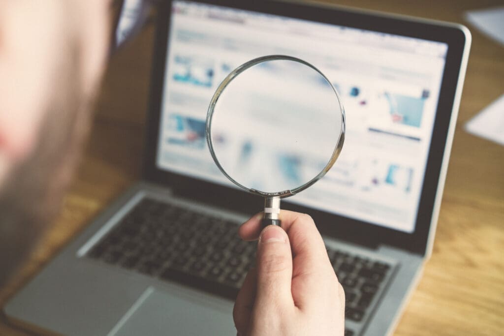 A person using a magnifying glass to look at a laptop screen